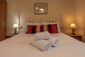 A neatly made bed with two pillows, a folded towel, and two bedside lamps. - The Old Smithy, 2 bedroom apartment - Pass the Keys (Shropshire)