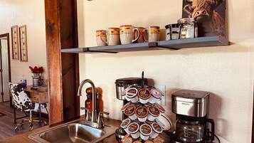 Cozinha com cafeteira, porta-xícaras e pôster com tema de café.