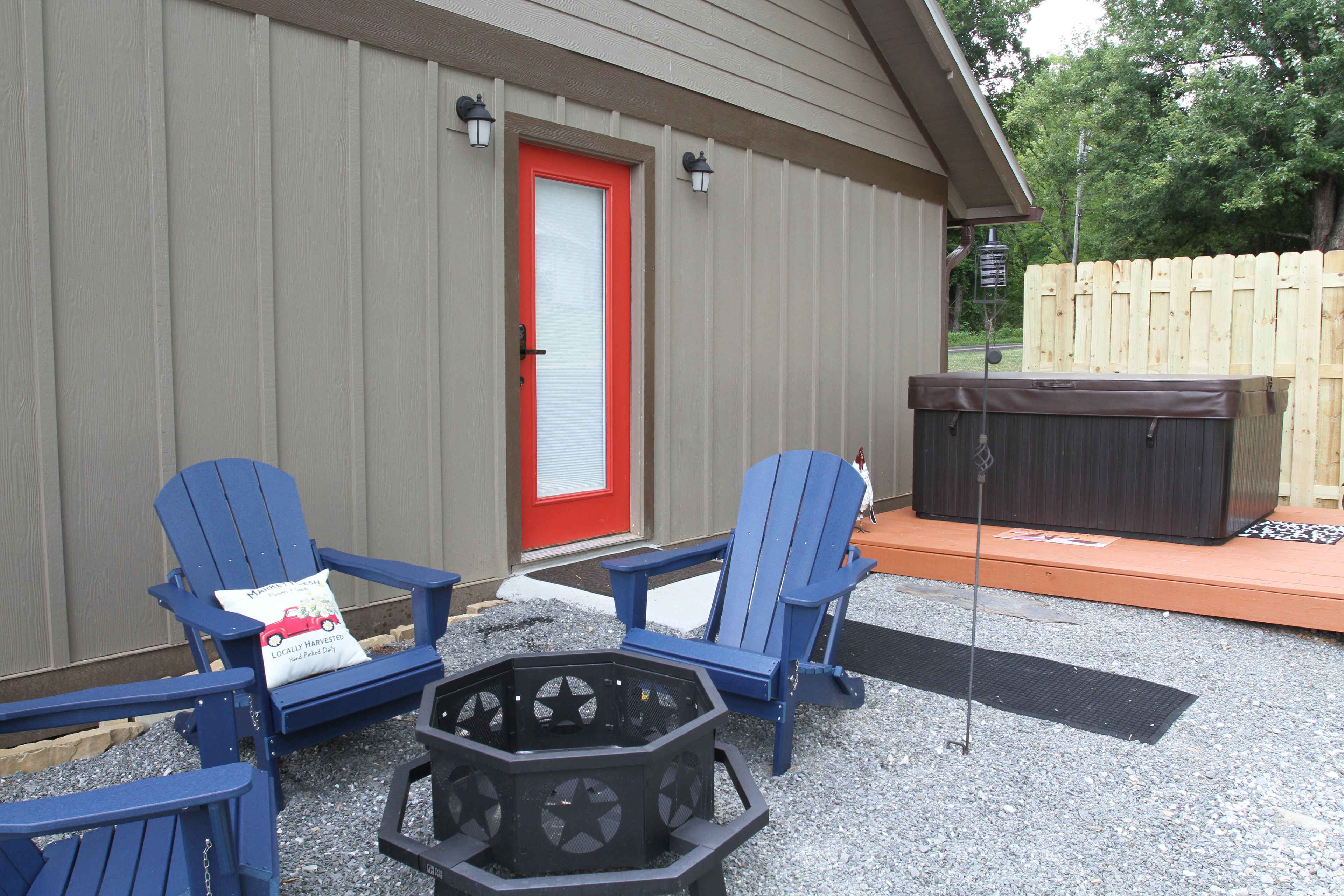 Un espace patio comprenant deux chaises Adirondack bleues, un foyer et un jacuzzi.