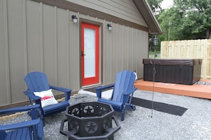 A patio area with two blue Adirondack chairs, a fire pit, and a hot tub.