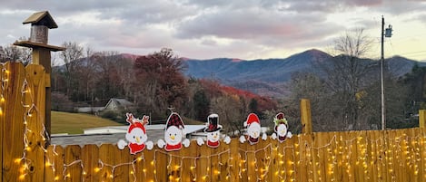 A wooden fence with string lights and paper cutouts of snowmen.