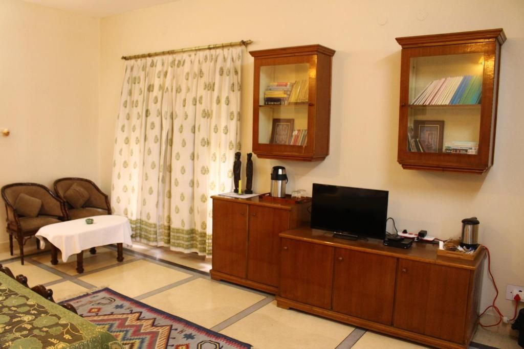 A living room with a television, wooden cabinets, a coffee table, two chairs, and a patterned rug.