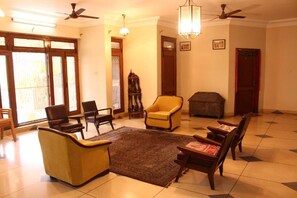 A spacious living room with a large window, a fireplace, and multiple seating options including a sofa and armchairs. - Savrupson Heritage Home (Jalandhar)