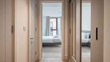 A hallway leading to a bedroom with a bed and a window.