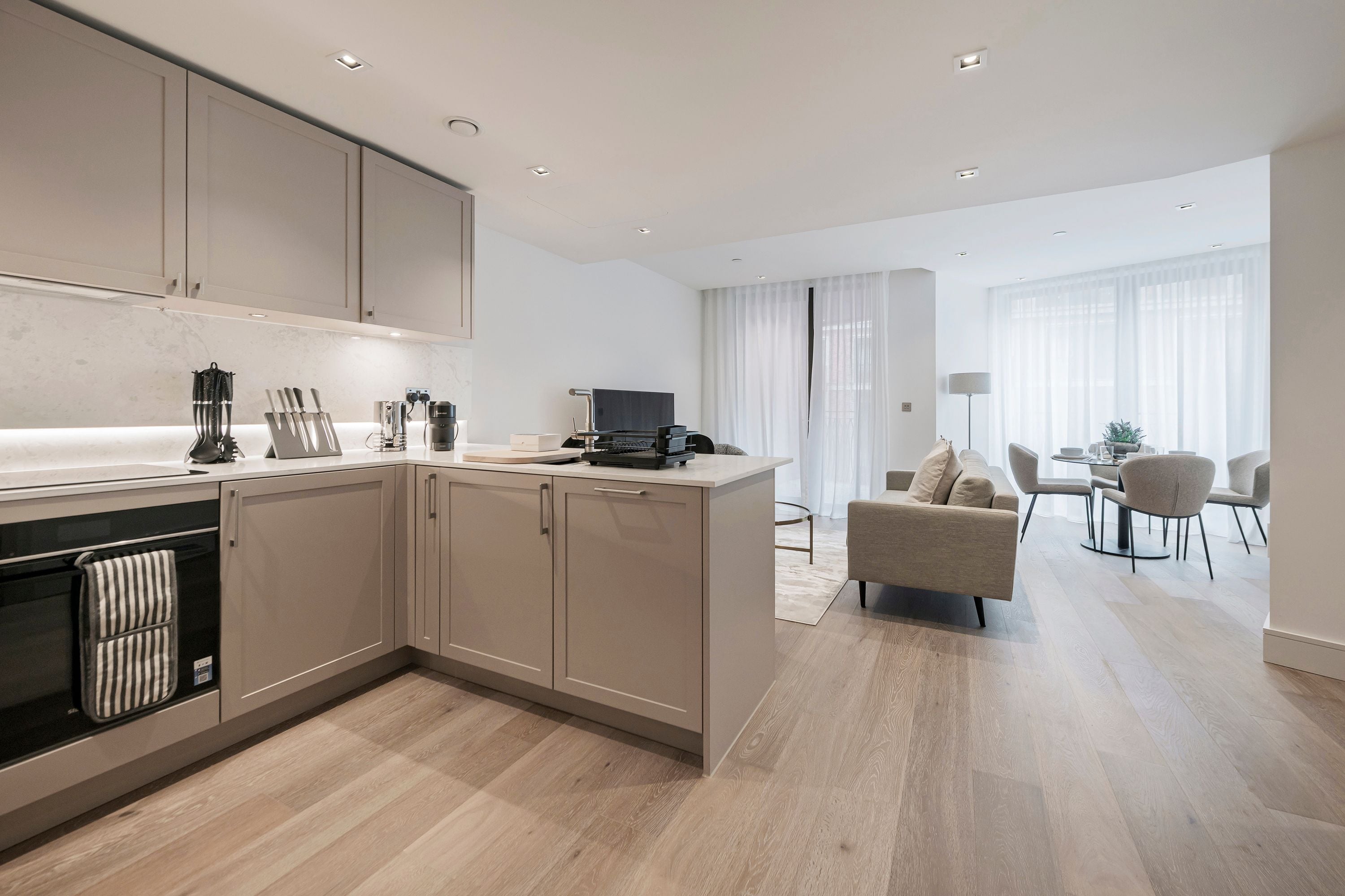 A modern kitchen with a central island, built-in appliances, and a dining area with a sofa and chairs.