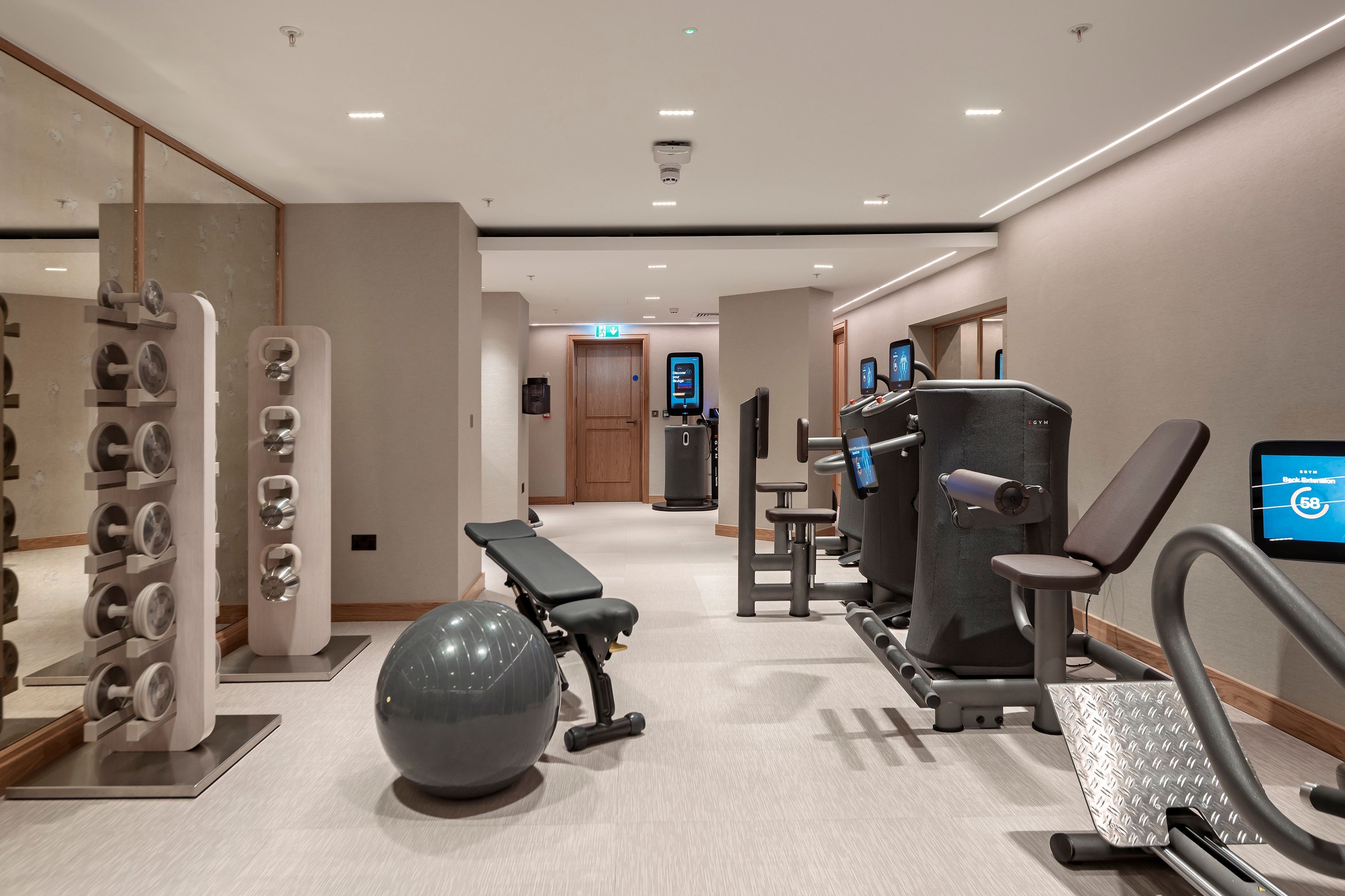 A modern gym with exercise equipment, a mirrored wall, and a clean, minimalist design.