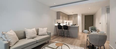 A modern living room with a sofa, a coffee table, and a dining area with chairs and a table.
