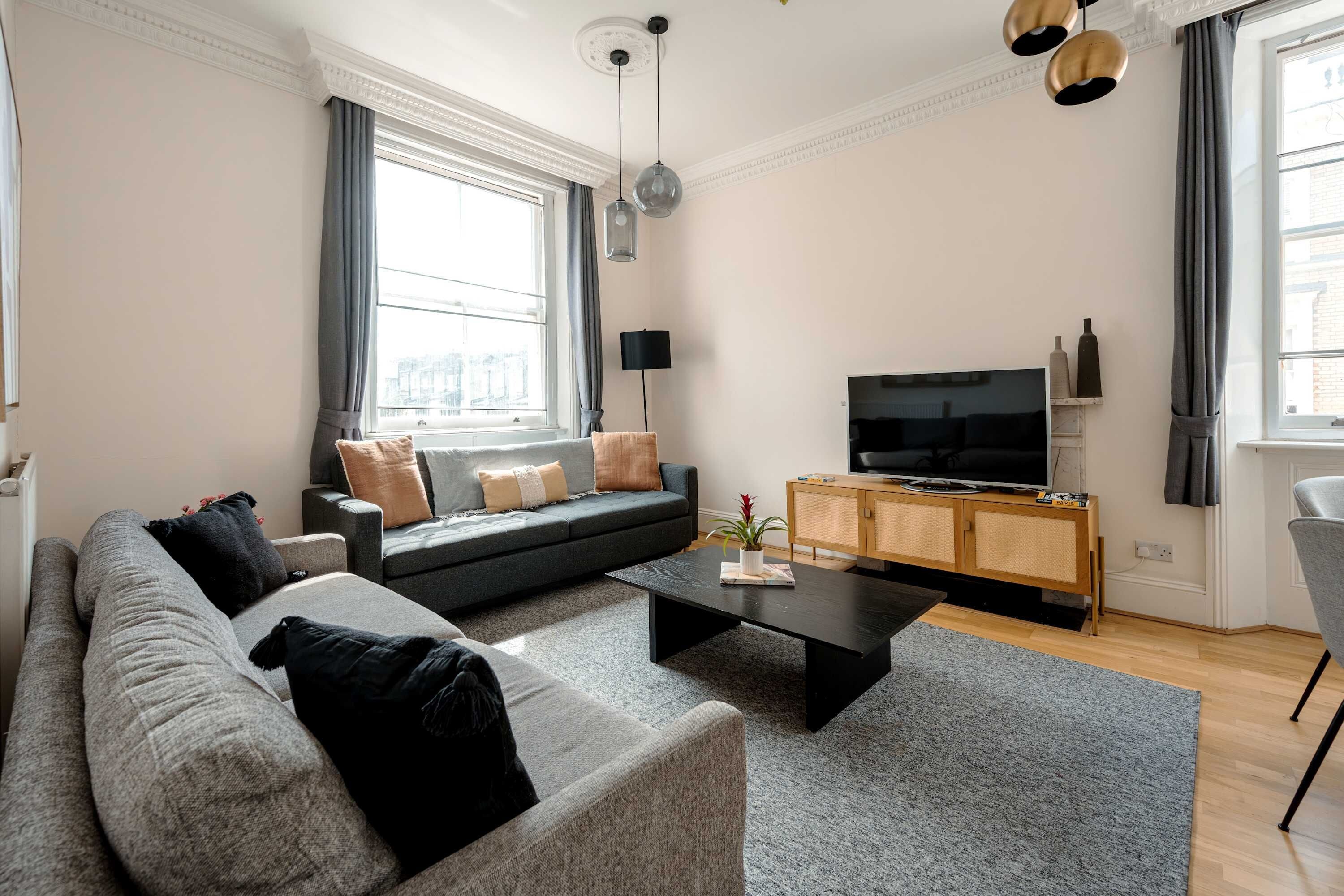 Un salon moderne avec un canapé, une table basse et un téléviseur posé sur un meuble en bois.