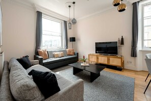 Ein stilvolles Wohnzimmer mit einer Couch, einem Couchtisch und einem Fernseher auf einer Holzkommode.