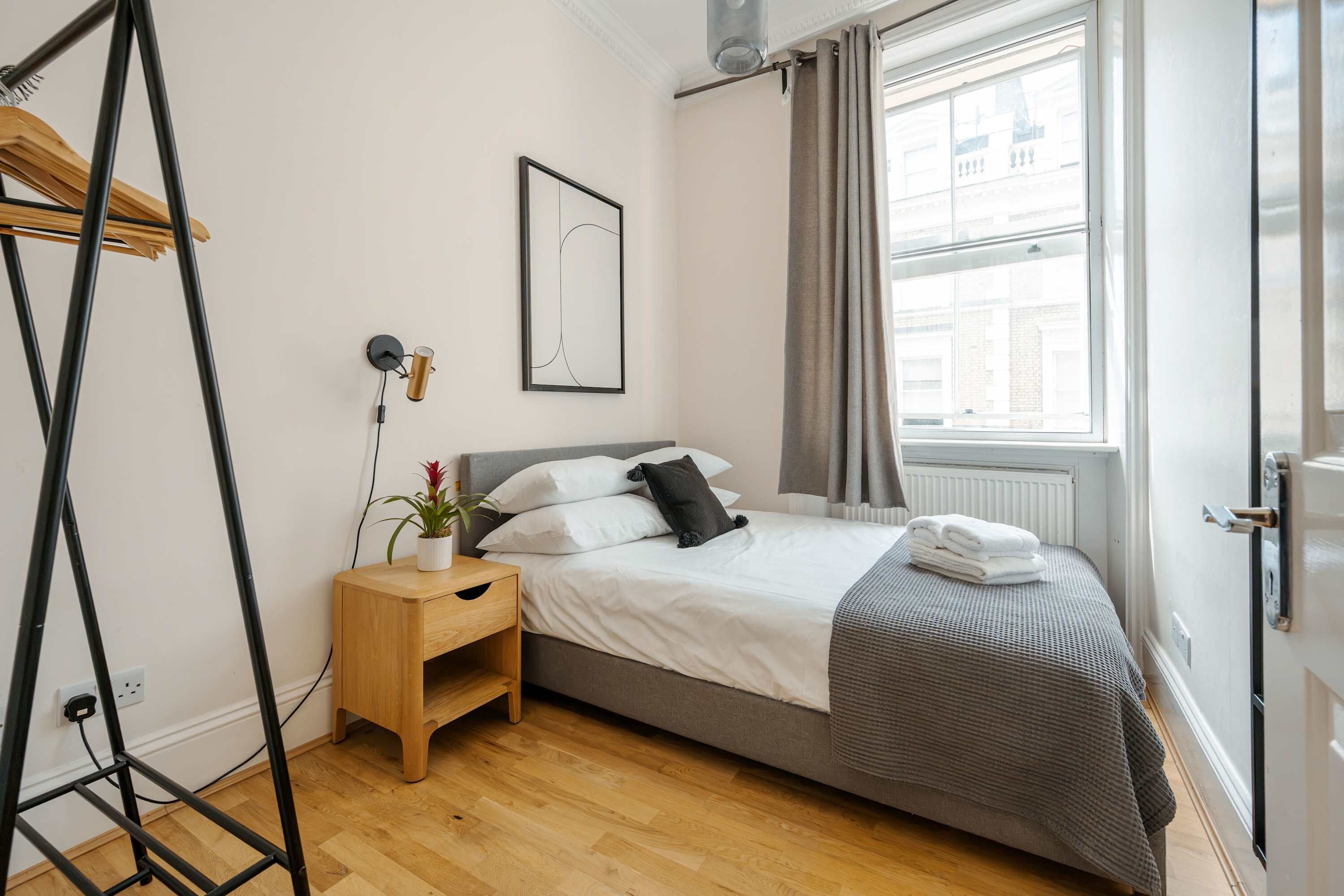 Une chambre à coucher avec un lit, une table de chevet et une fenêtre avec des rideaux.