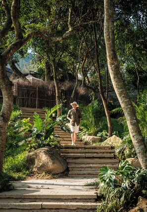 A person standing on a stone staircase surrounded by lush greenery and trees. - Xiaoyin Cuiweiyang Resort (Shenzhen)