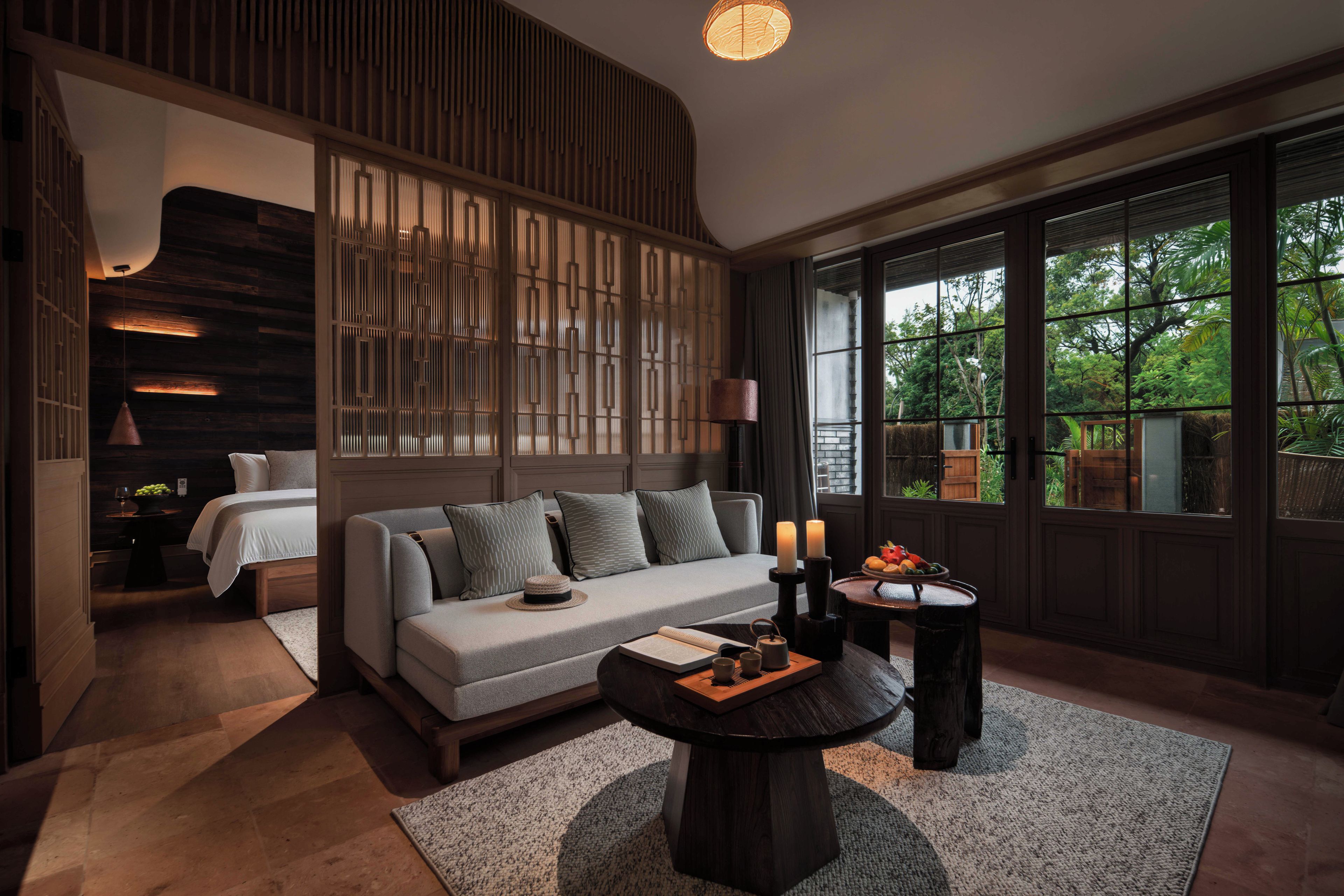 A modern interior with a sofa, a round coffee table, and a view of greenery outside.