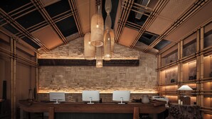 A reception area with a wooden reception desk, three computer monitors, and a large woven light fixture. - Xiaoyin Cuiweiyang Resort (Shenzhen)