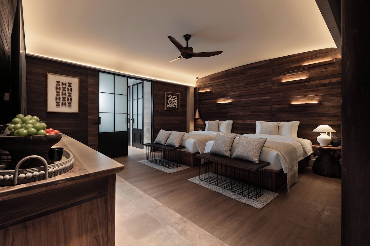 Quarto moderno com cama grande, mesas de cabeceira, ventoinha no teto e painel de parede em madeira.