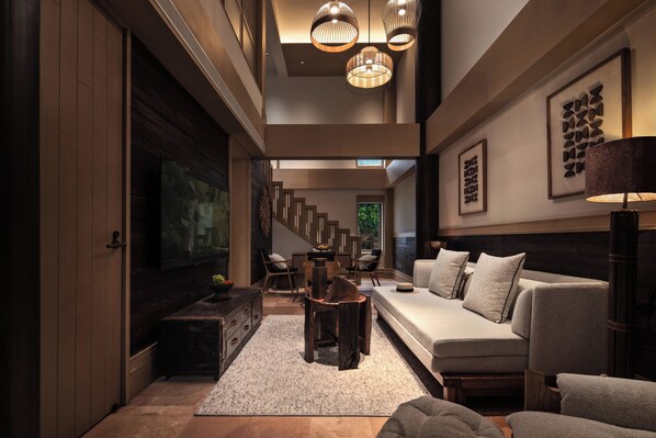 A modern interior with a sofa, chairs, a dining table, and a TV.