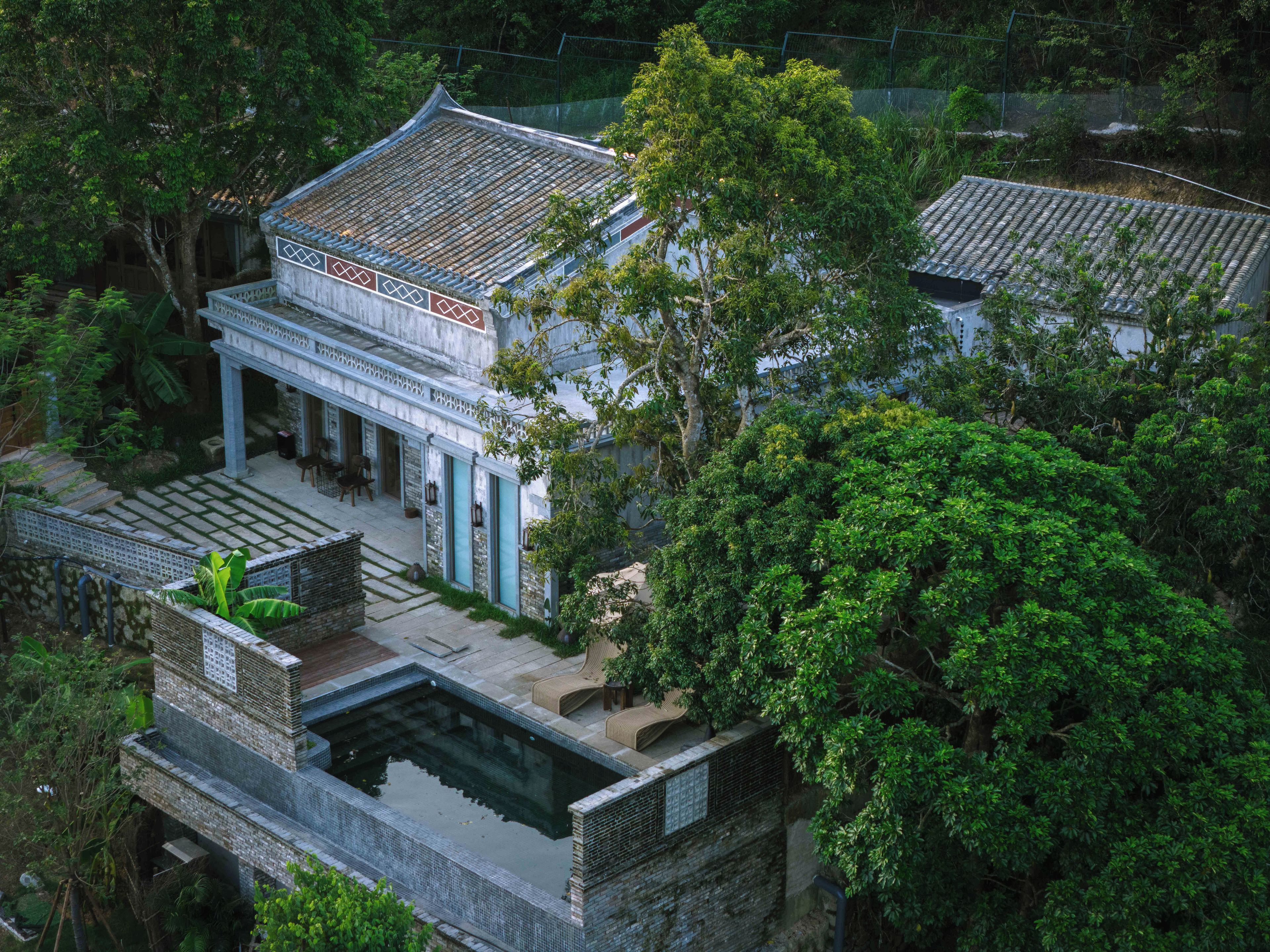 Un edificio tradicional con tejado de tejas, un patio cubierto y una piscina pequeña.