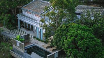 Un edificio tradicional con tejado de tejas, un patio cubierto y una piscina pequeña.
