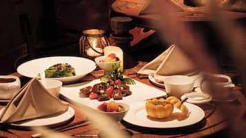 Un comedor con poca luz, con una mesa dispuesta para una comida, incluyendo platos, tazones y una vela.