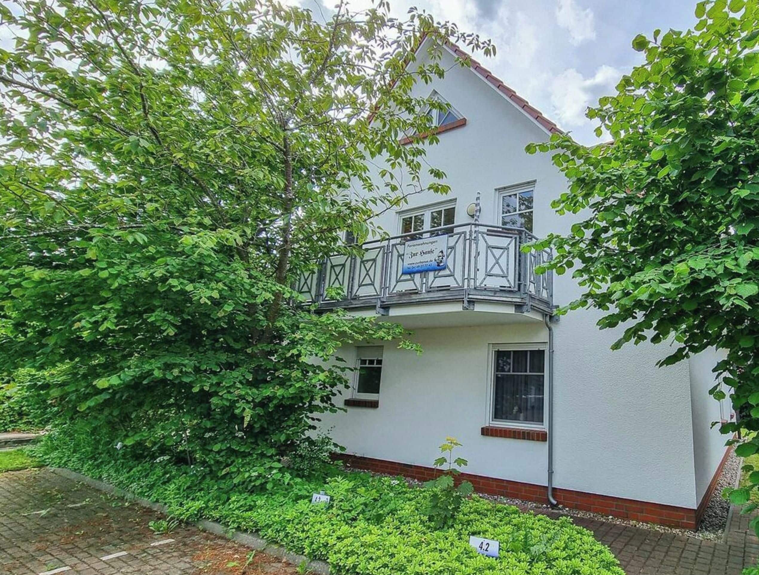 Un immeuble de deux étages doté d’un balcon et d’un petit jardin.