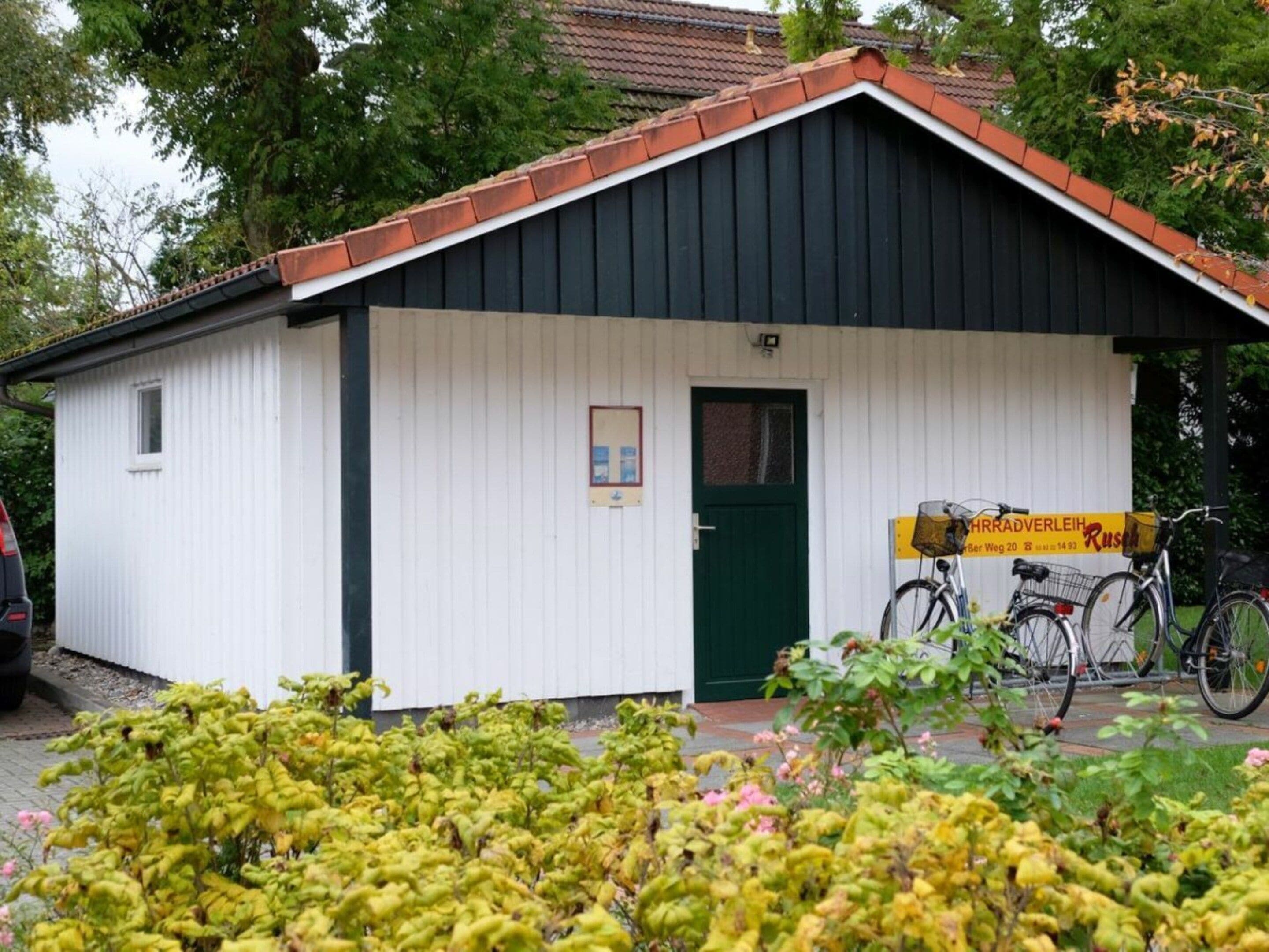 A small building with a green door, a signboard, and bicycles parked outside.