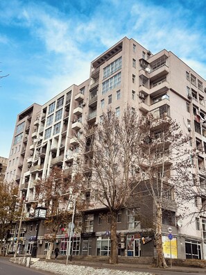 A multi-story building with balconies, a street in front, and some trees. - Modern Apartment with Balcony & WiFi (T'bilisi)