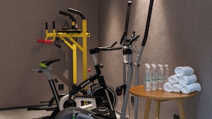 En motionscykel, et løbebånd og et bord med vand på flaske og håndklæder.