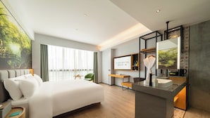 Et moderne hotelværelse med en stor seng, et skrivebord, et fjernsyn og et badeværelse med håndvask og spejl.