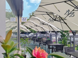 An outdoor seating area with umbrellas and tables, surrounded by potted plants. - The Skytel IMCC Shenzhen (Shenzhen)