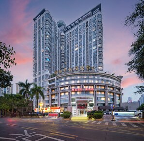 A modern hotel with a curved facade, multiple floors, and a prominent entrance.