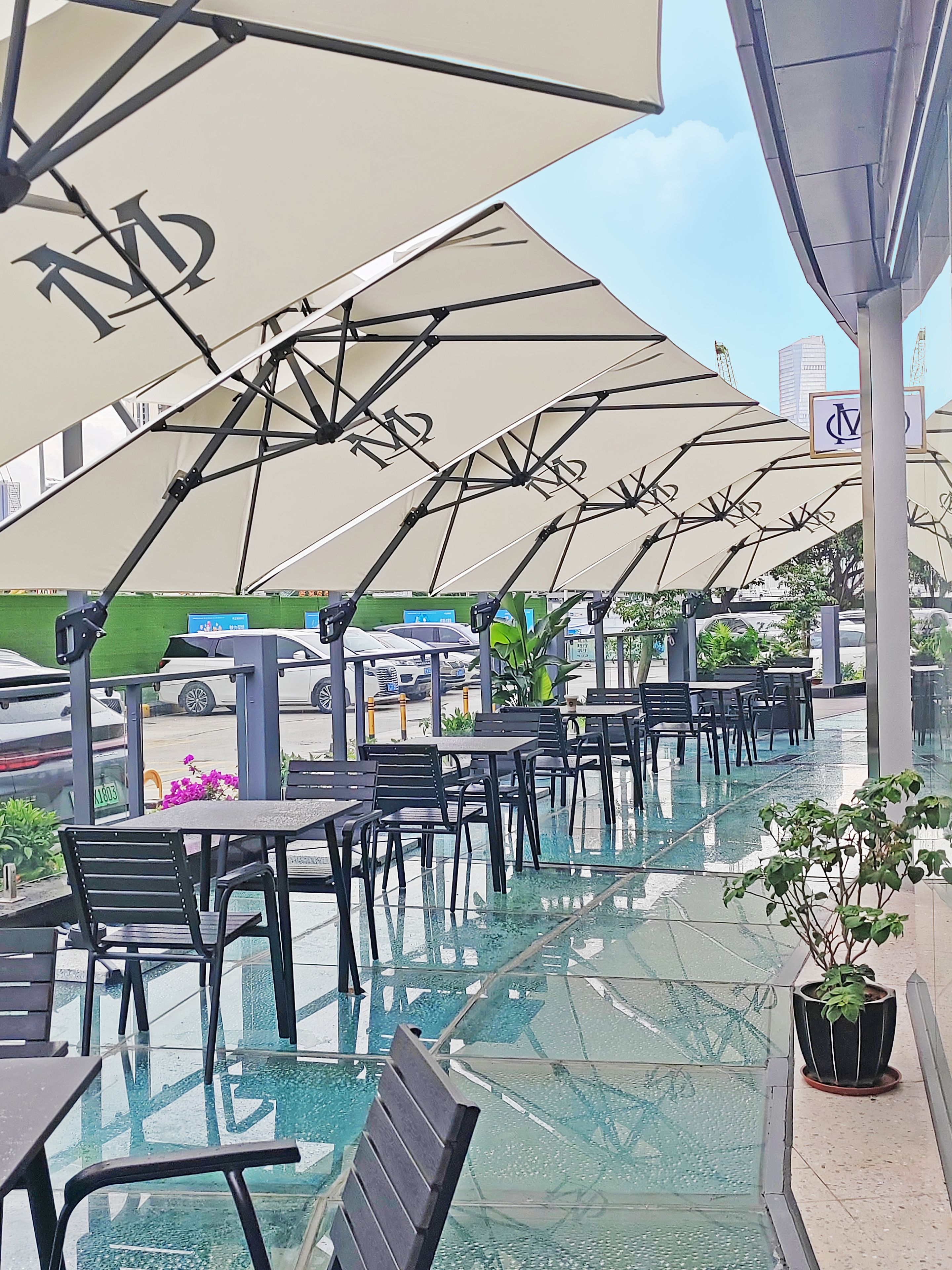 Outdoor seating with umbrellas, a glass-tiled floor, and a view of the street.