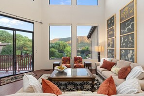 A spacious living room with a large window, a sofa set, a coffee table, and a decorative wall with artwork. - Les Clés ~ Sedona (Sedona)