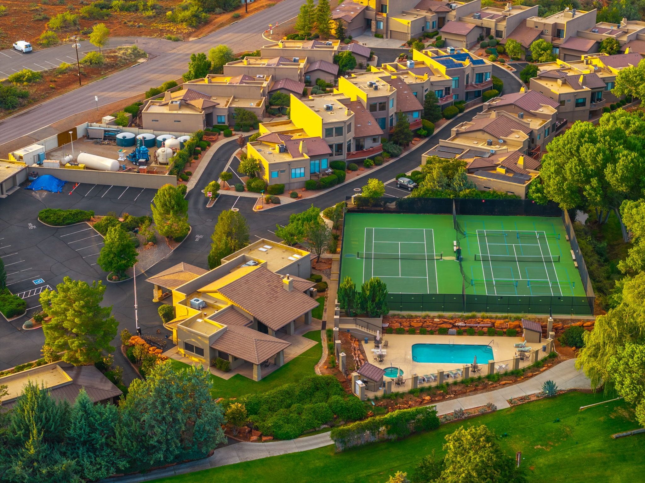 A residential area with multiple houses, a tennis court, and a swimming pool.