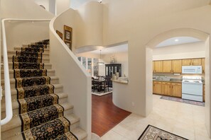 A staircase with ornate carpet, a kitchen with wooden cabinets and white appliances, and a dining area with a chandelier. - Les Clés ~ Sedona (Sedona)