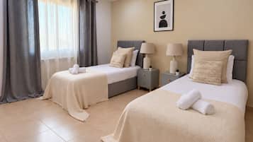 Een hotelkamer met twee bedden, een raam met gordijnen, nachtkastjes met lampen en een lijst aan de muur.
