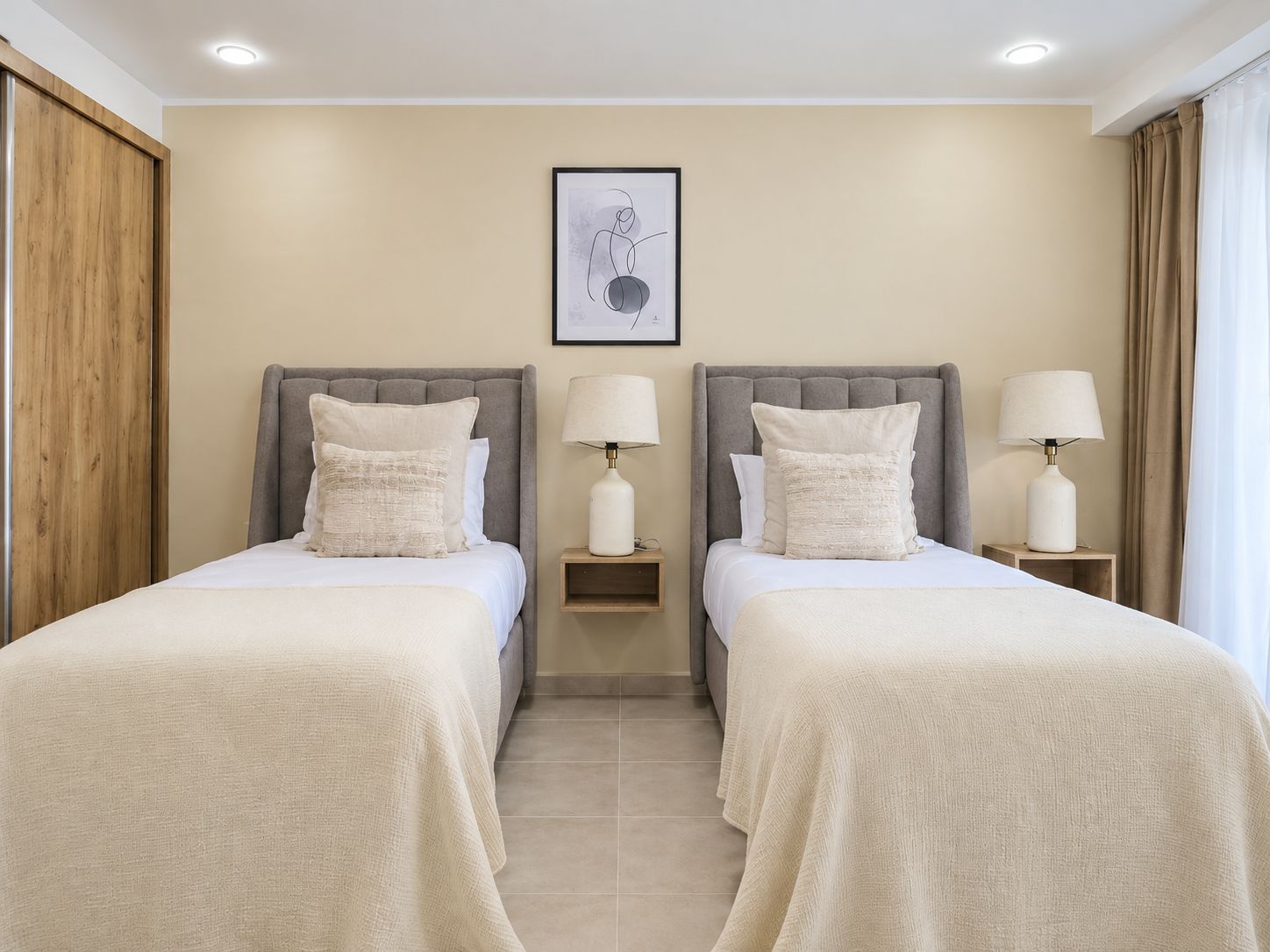 A hotel room with two beds, each with a nightstand and a lamp.