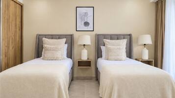 A hotel room with two beds, each with a nightstand and a lamp.