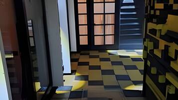 A hallway with a checkered floor pattern, a door with a window, and a wall with a geometric design.