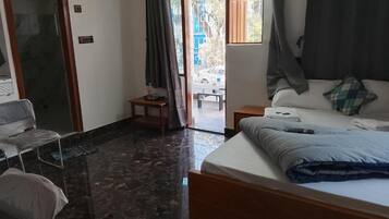 Une chambre d’hôtel comprenant un lit, une chaise, une petite table et une porte coulissante donnant sur un espace extérieur.