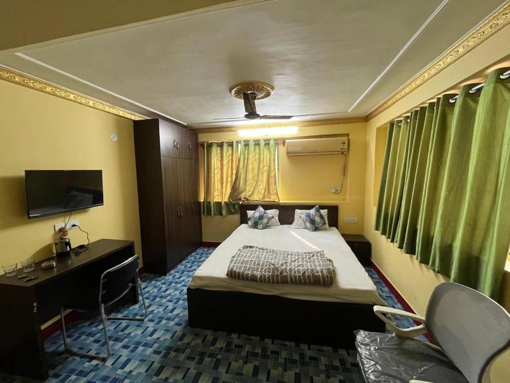 A hotel room with a bed, a desk, a television, and a ceiling fan.