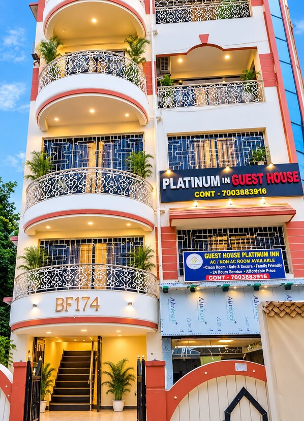 A multi-story building with balconies, a contact number, and a sign for a Platinum in Guest House.