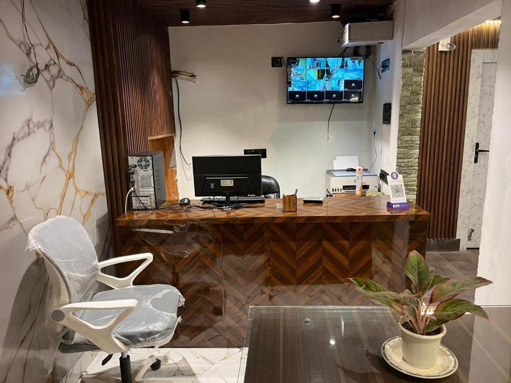 A reception desk with a television, a computer, and a plant.