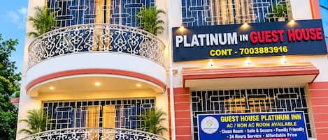 Un edificio de varios pisos con balcones, un letrero que dice Platinum Guest House, y un número de contacto.