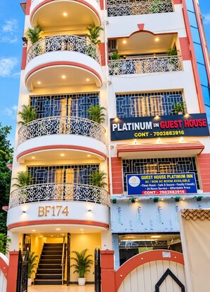 Un edificio de varios pisos con balcones, un letrero que dice Platinum Guest House, y un número de contacto.