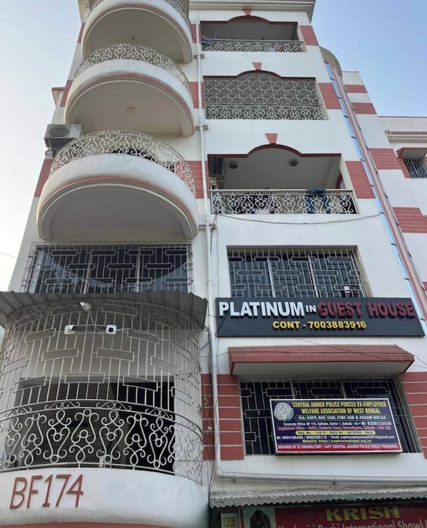A multi-story building with balconies, a sign for 'Platinum in Guest House,' and a visible building number 'BF174.'