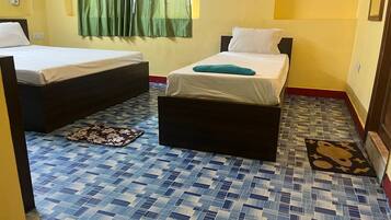 A room with two beds, a patterned floor, and a green curtain.