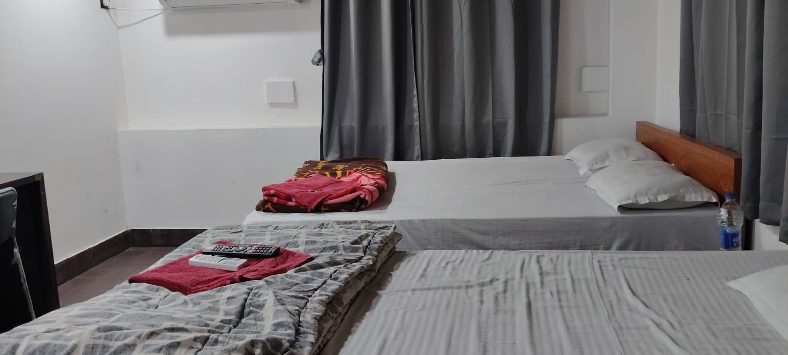 A hotel room with two beds, a desk, and a chair.