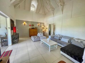 A spacious living room with a high ceiling, a sofa set, a coffee table, and a wooden cabinet. - Just 650 meters from the ocean! 4-bedroom villa with a large pool and bar area (Saint-François)