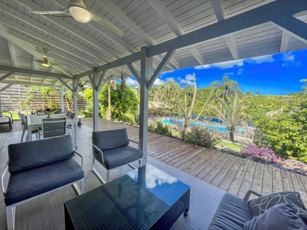 Una terrazza esterna con vista sulla piscina, sedute coperte e un tavolo.