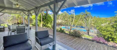 An outdoor patio with a pool view, covered seating, and a table.