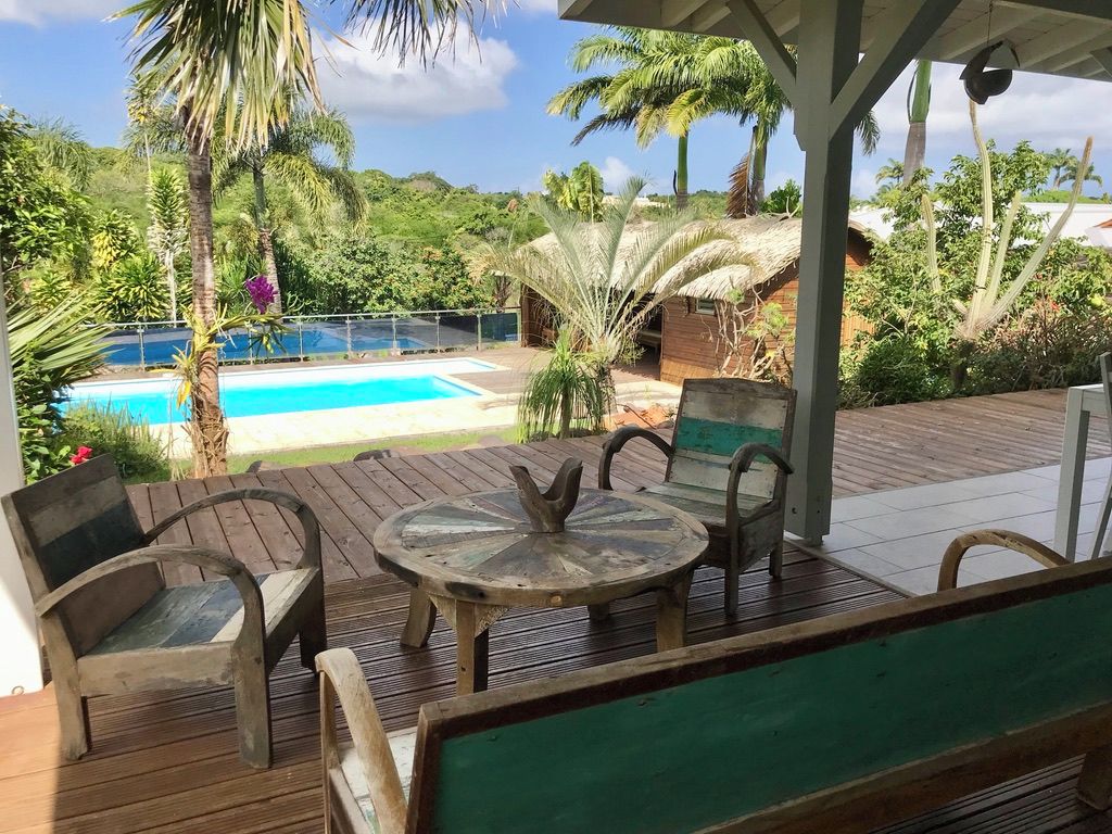 Une terrasse en bois avec une piscine, des chaises et une table.
